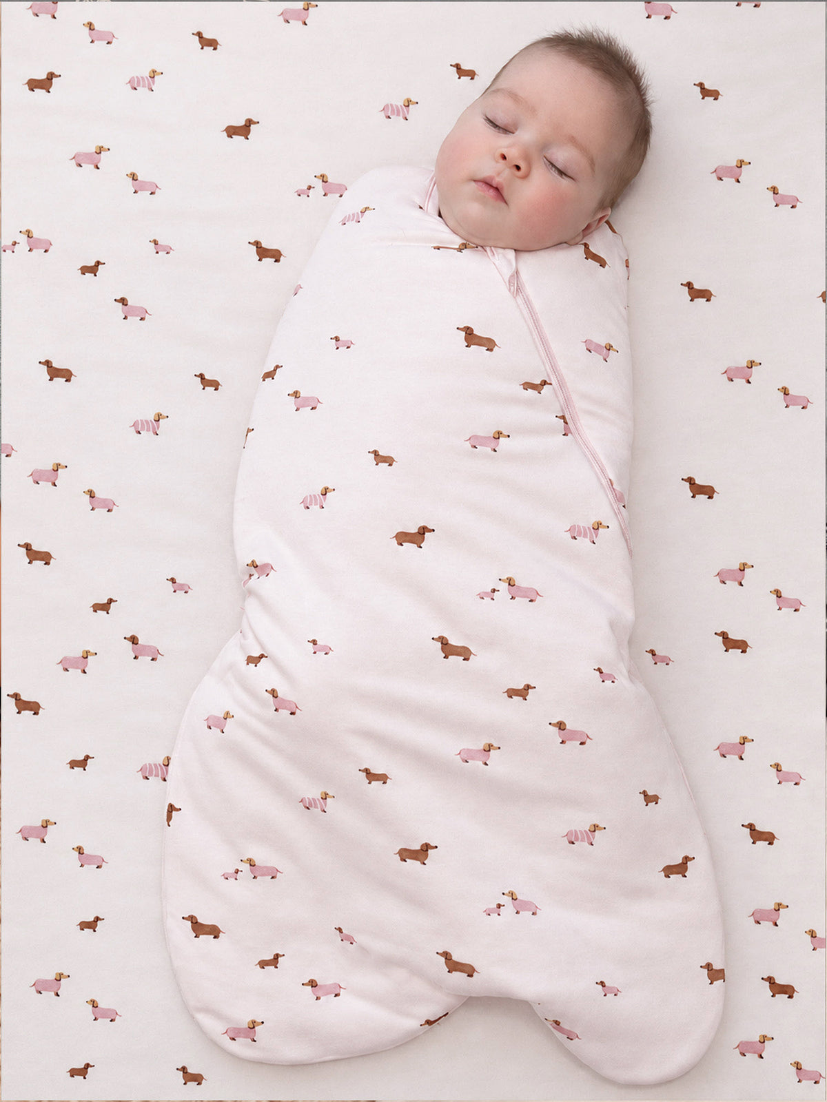 Crib sheet fabric with repeating dog and farm-animal print in pink and tan
