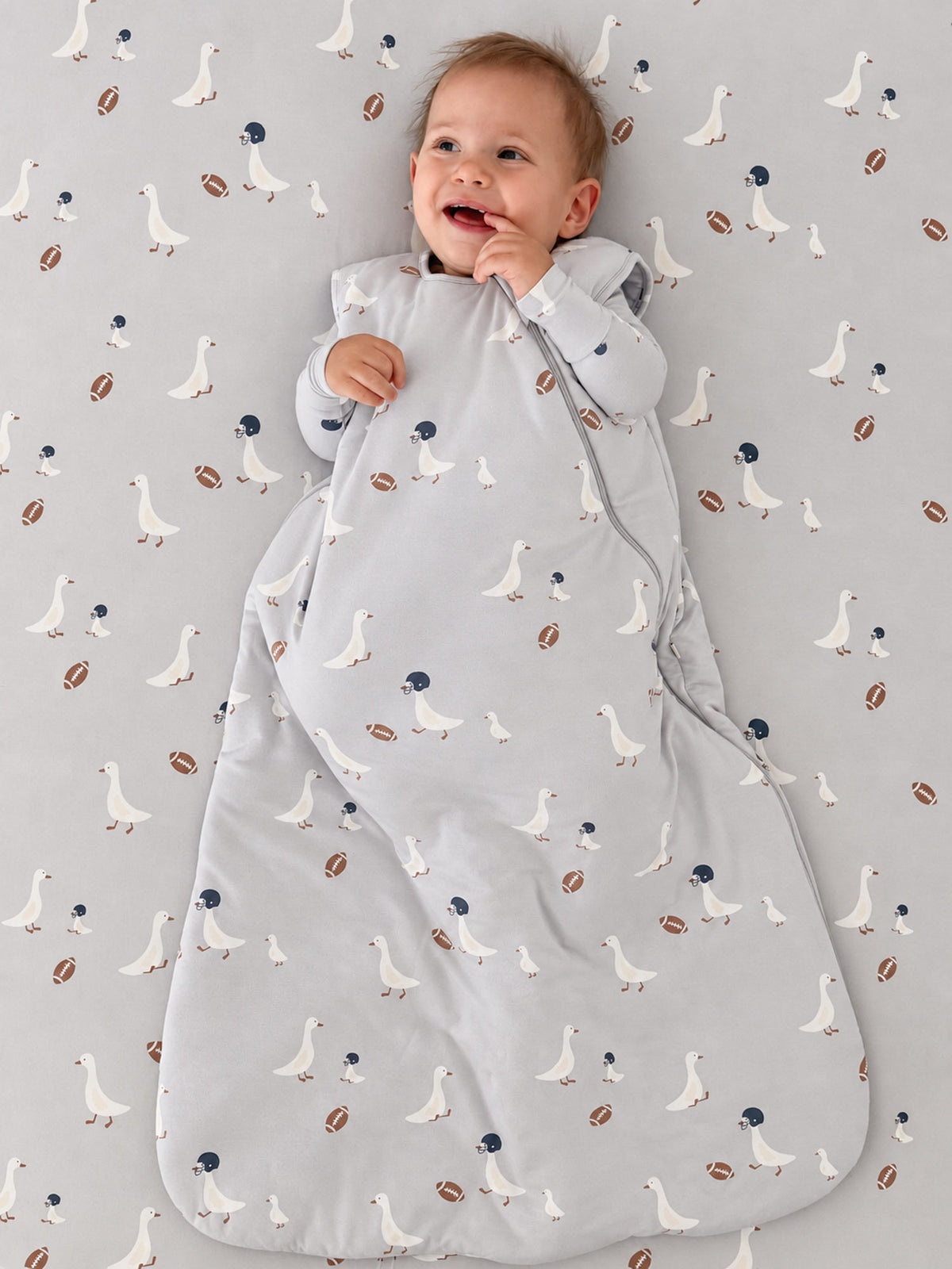 Light gray sleep sack with goose and football pattern, front view with arms out