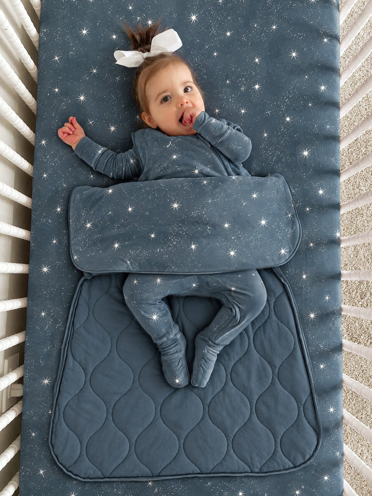 Dark blue star-print sleep sack with long sleeves and leg opening, toddler wearing