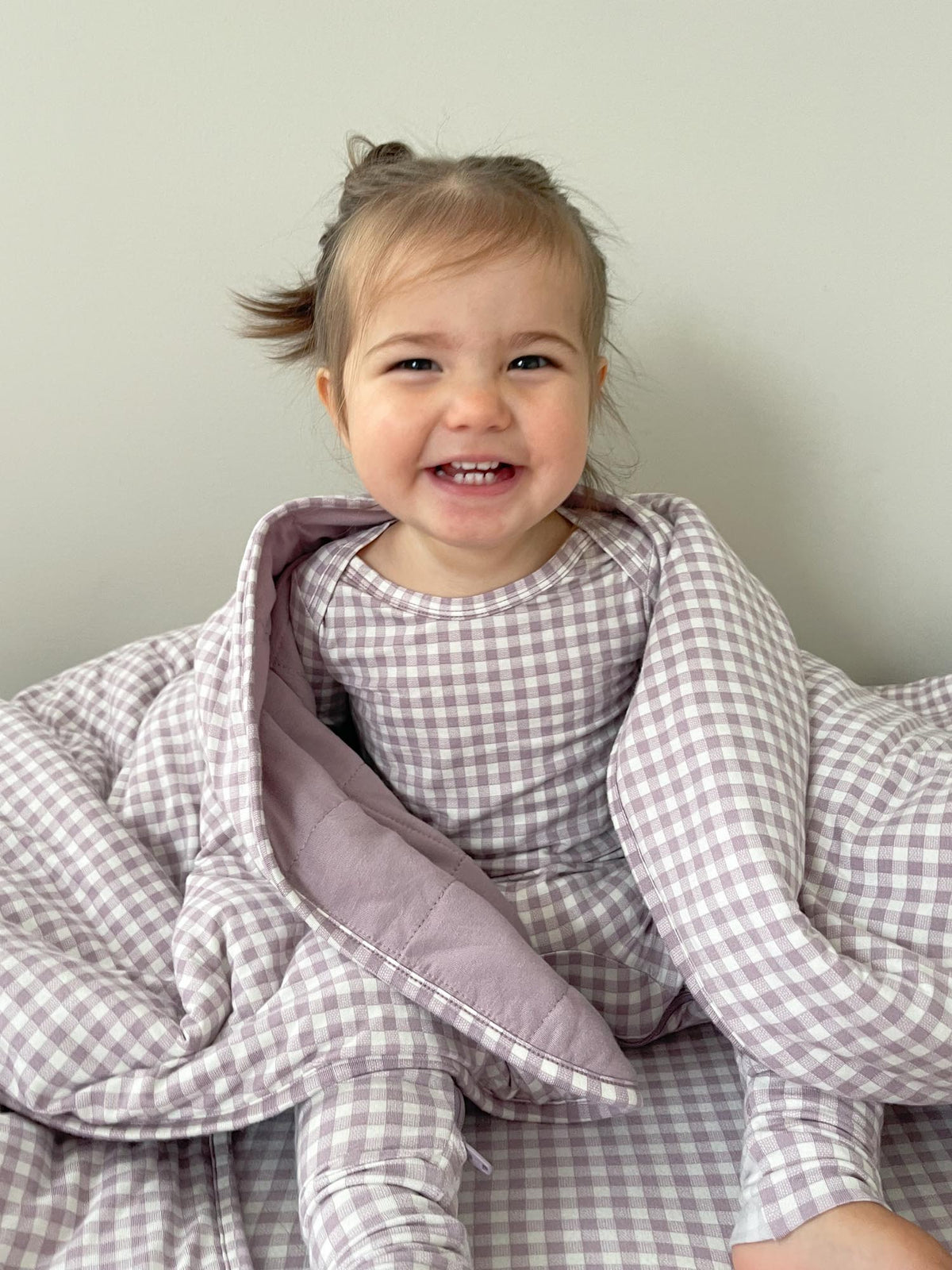 Hooded baby blanket with lilac hood and gray gingham, baby leaning forward