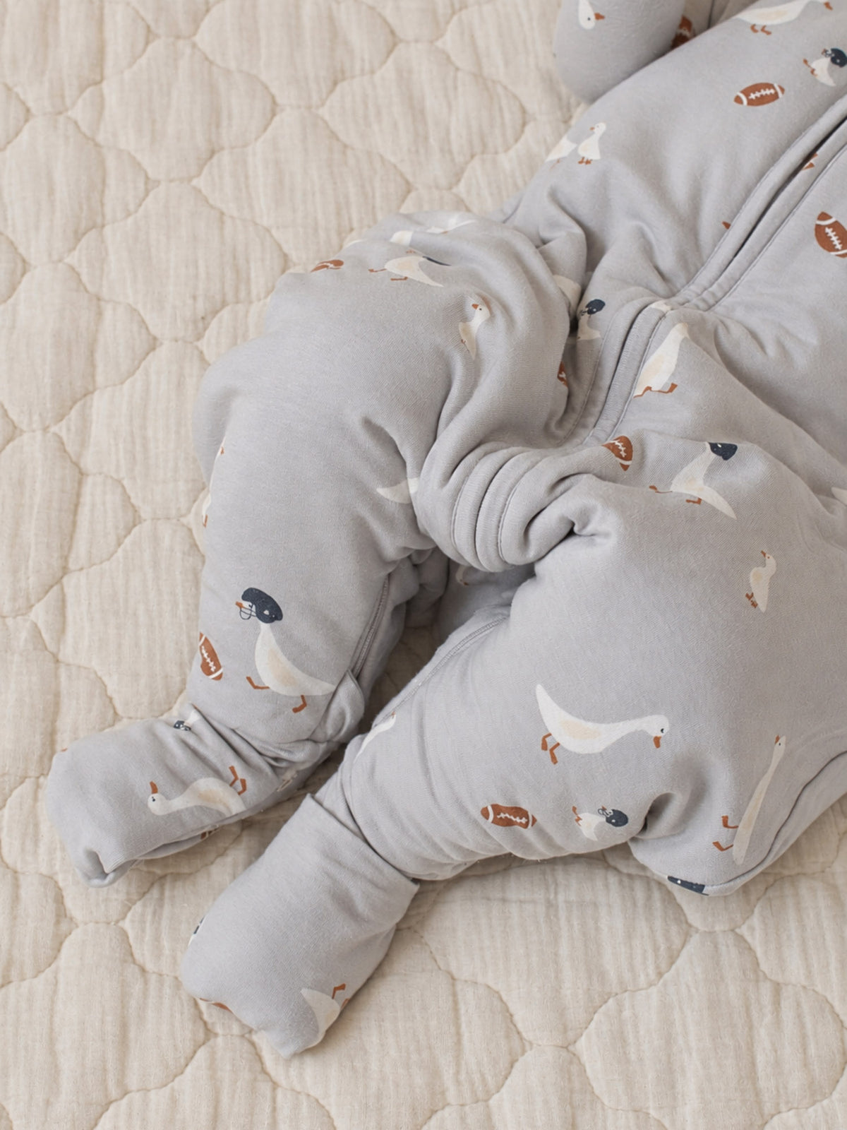 Baby footie sleep sack in light gray with football and goose prints, close-up