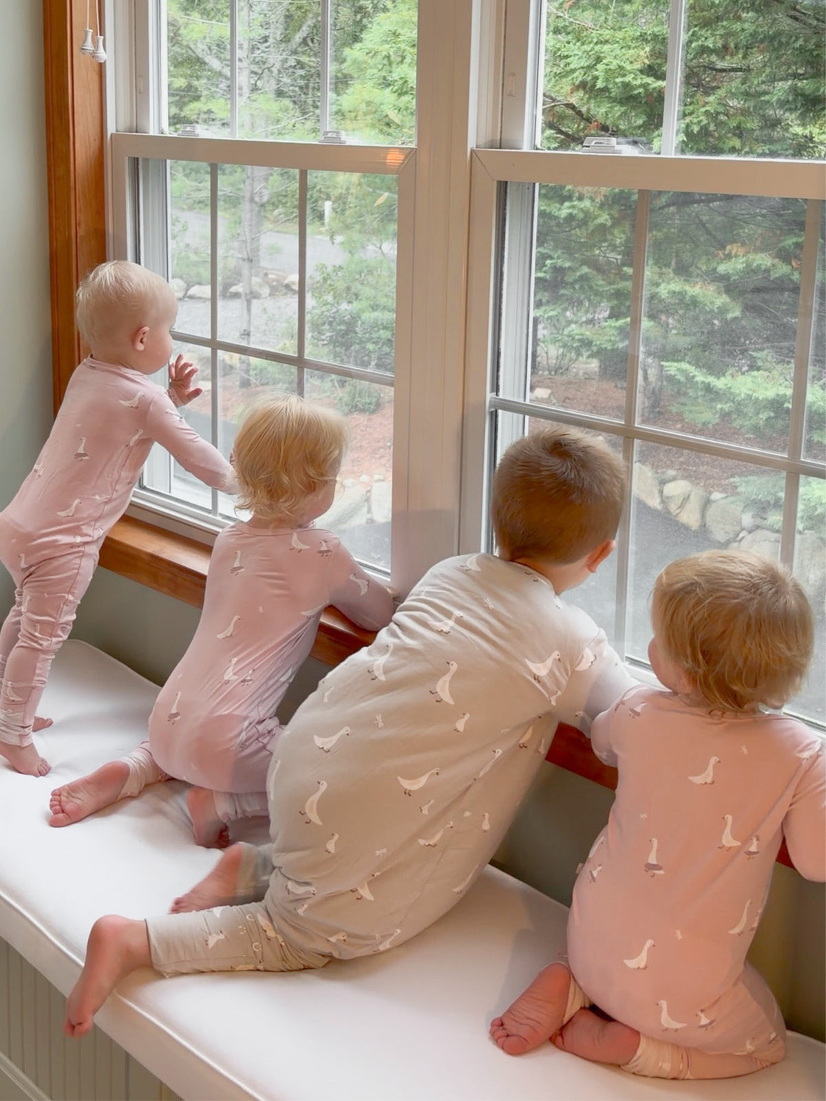 Pink duck-print convertible pajama worn by three children on a window seat