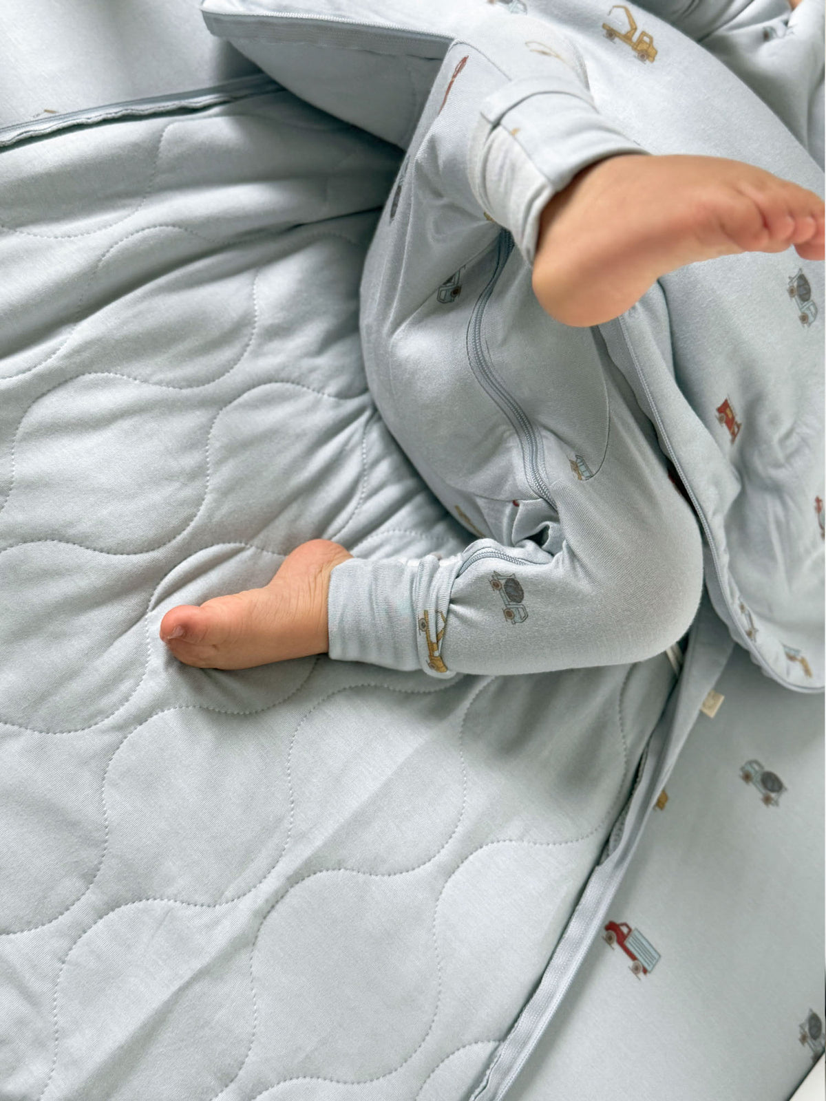 2.5 TOG baby sleep sack close-up: light blue quilted fabric with vehicle print, zipper opening