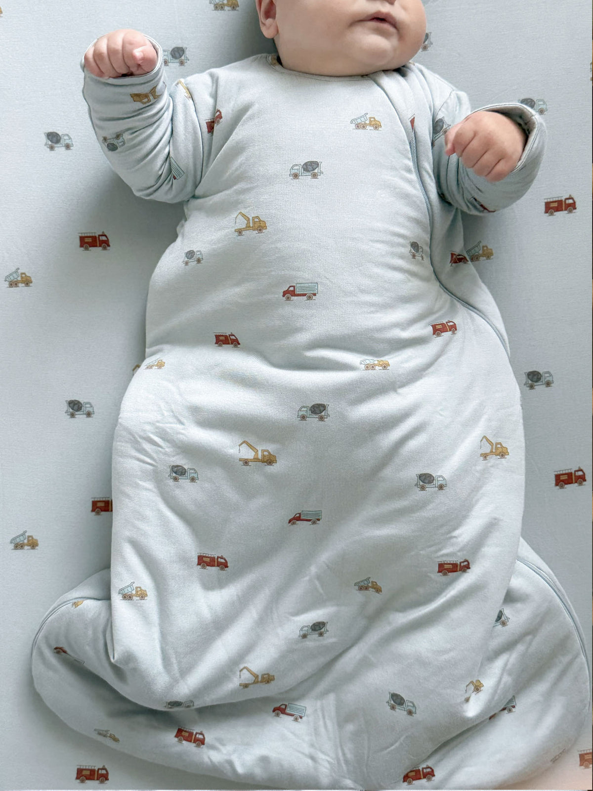 Long-sleeve swaddle sack with vehicle print, light gray; baby wearing it