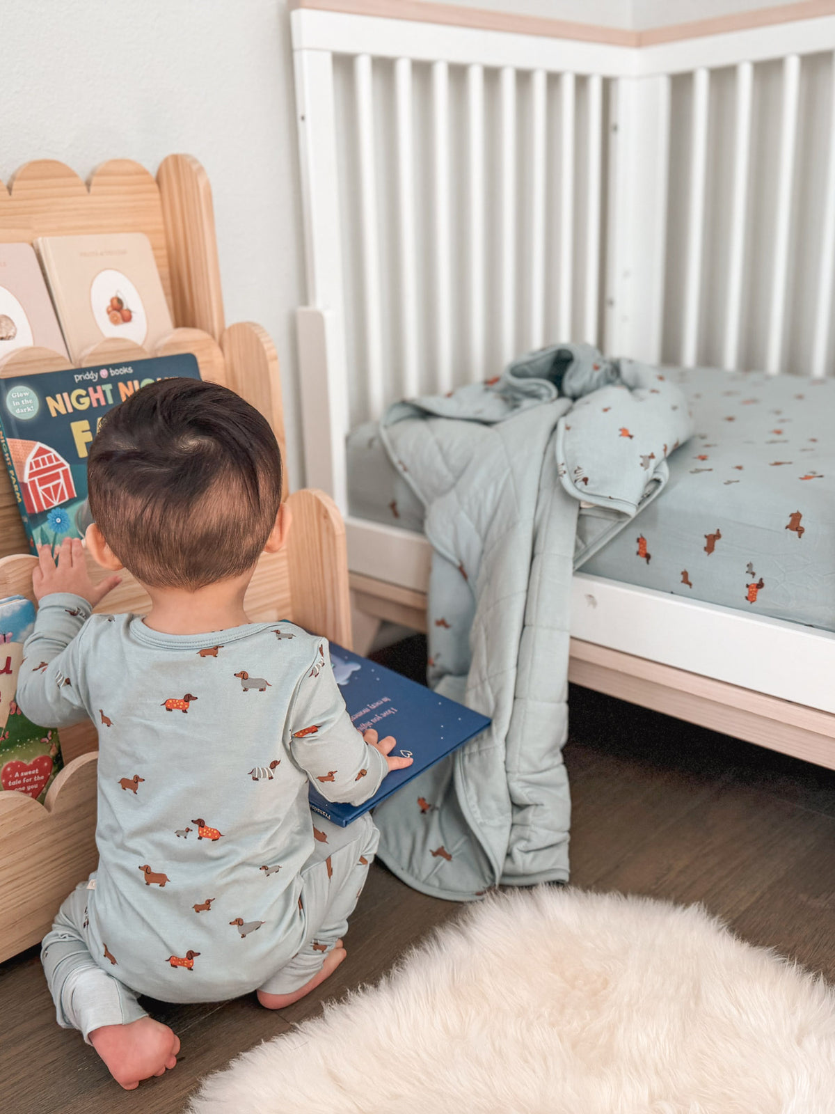Light blue animal-print blanket on a cot, with a baby nearby
