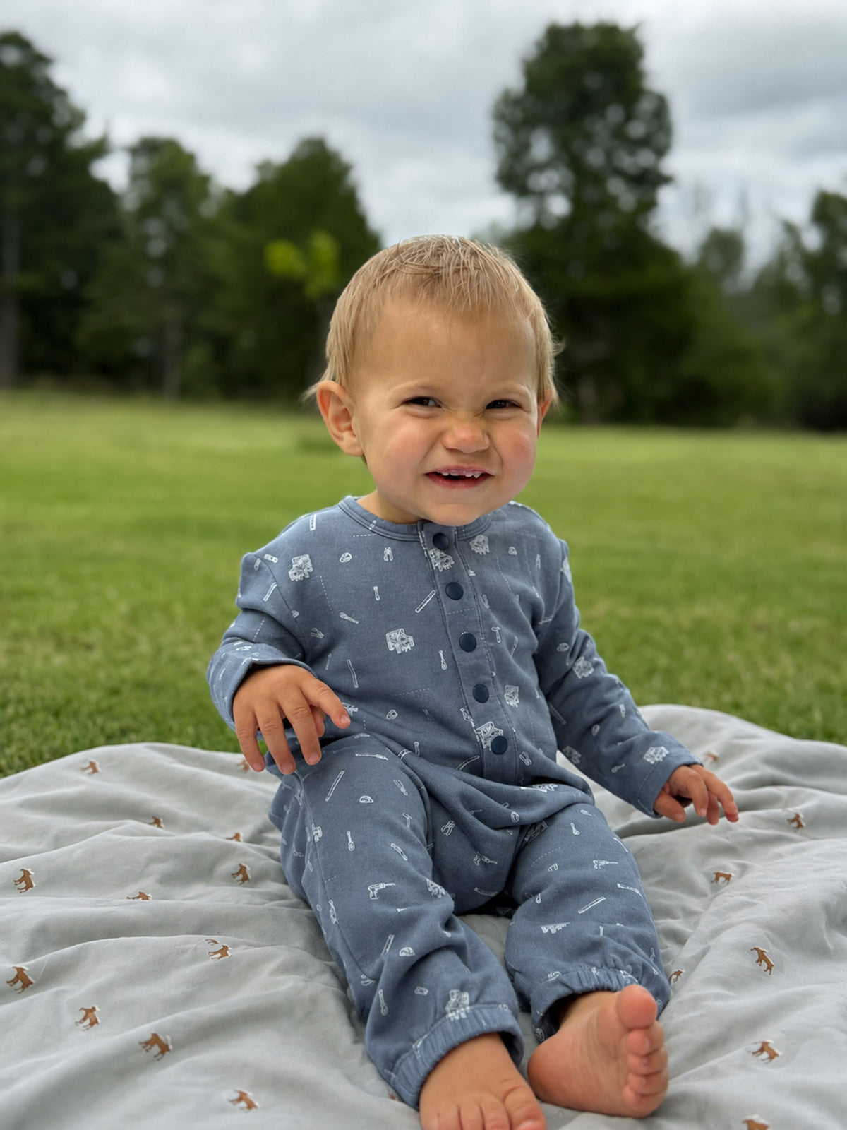 Blue tool-print henley jumpsuit with button-front and footed legs