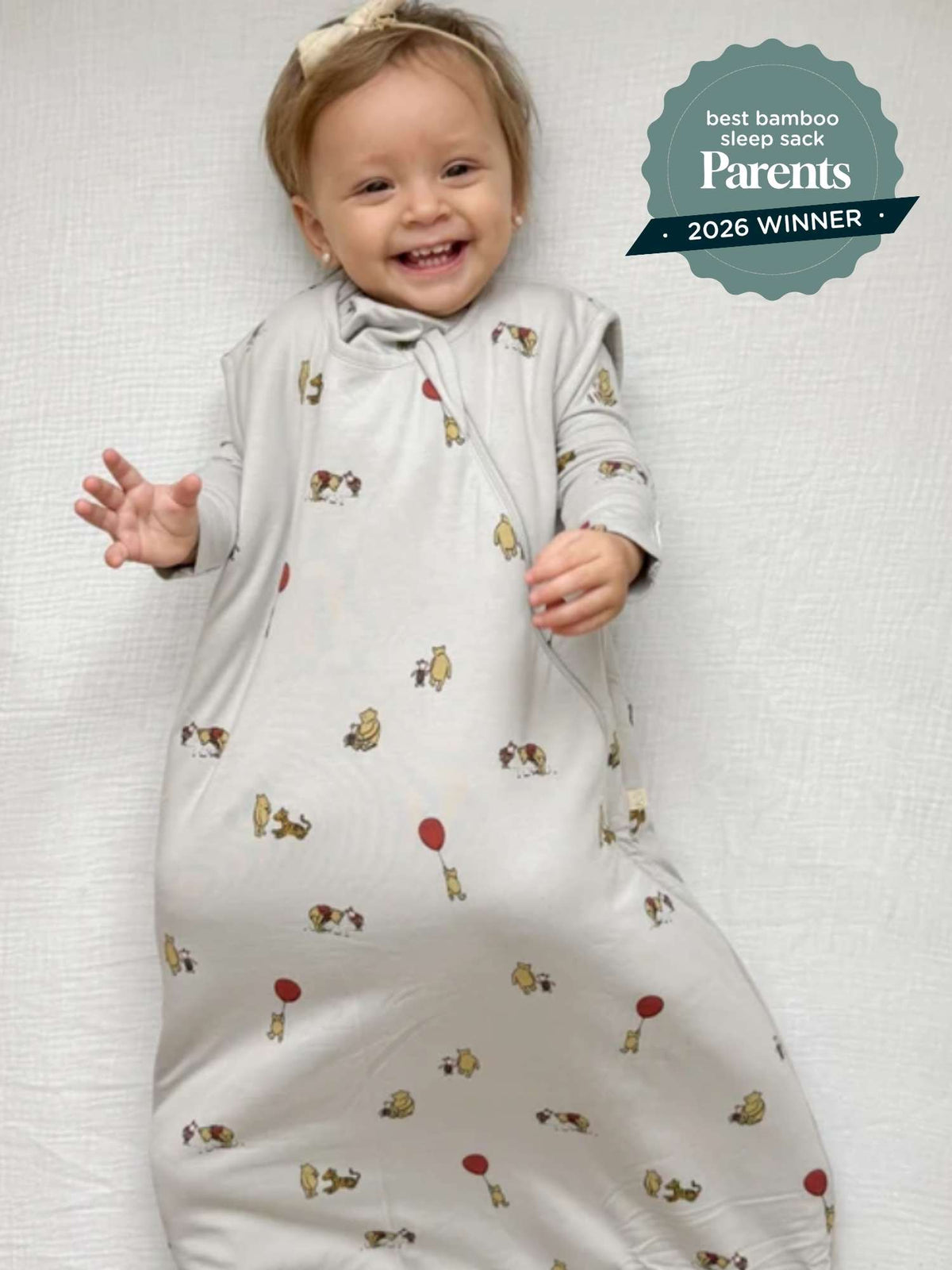 White baby sleep sack with Pooh character print, baby smiling inside with arms out