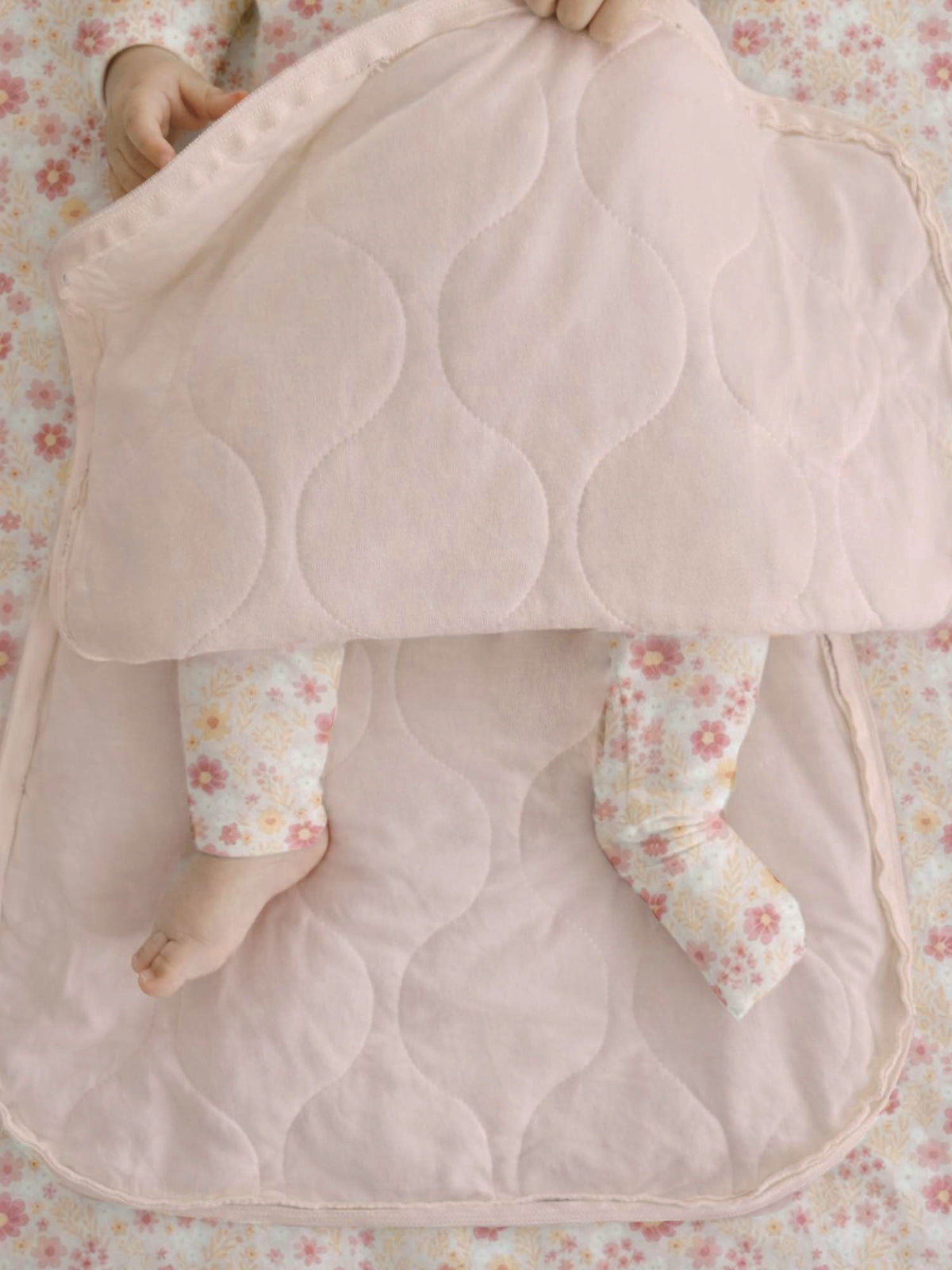 Unzipped swaddle sleep sack lining with quilted cloud pattern, soft pink and beige.