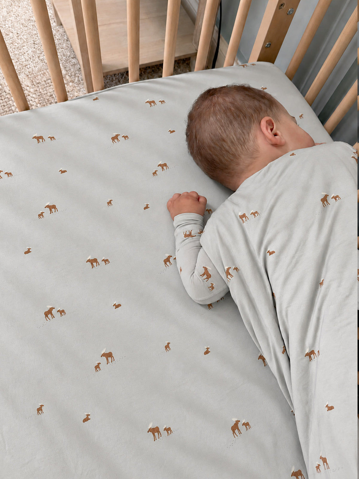 Light gray crib sheet with small moose print, fitted corners