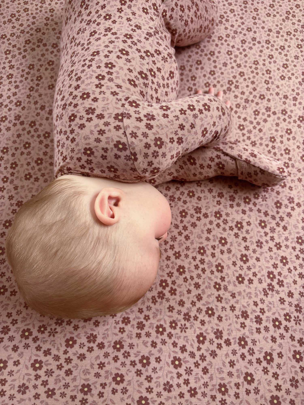 Light pink crib sheet with small petal floral pattern