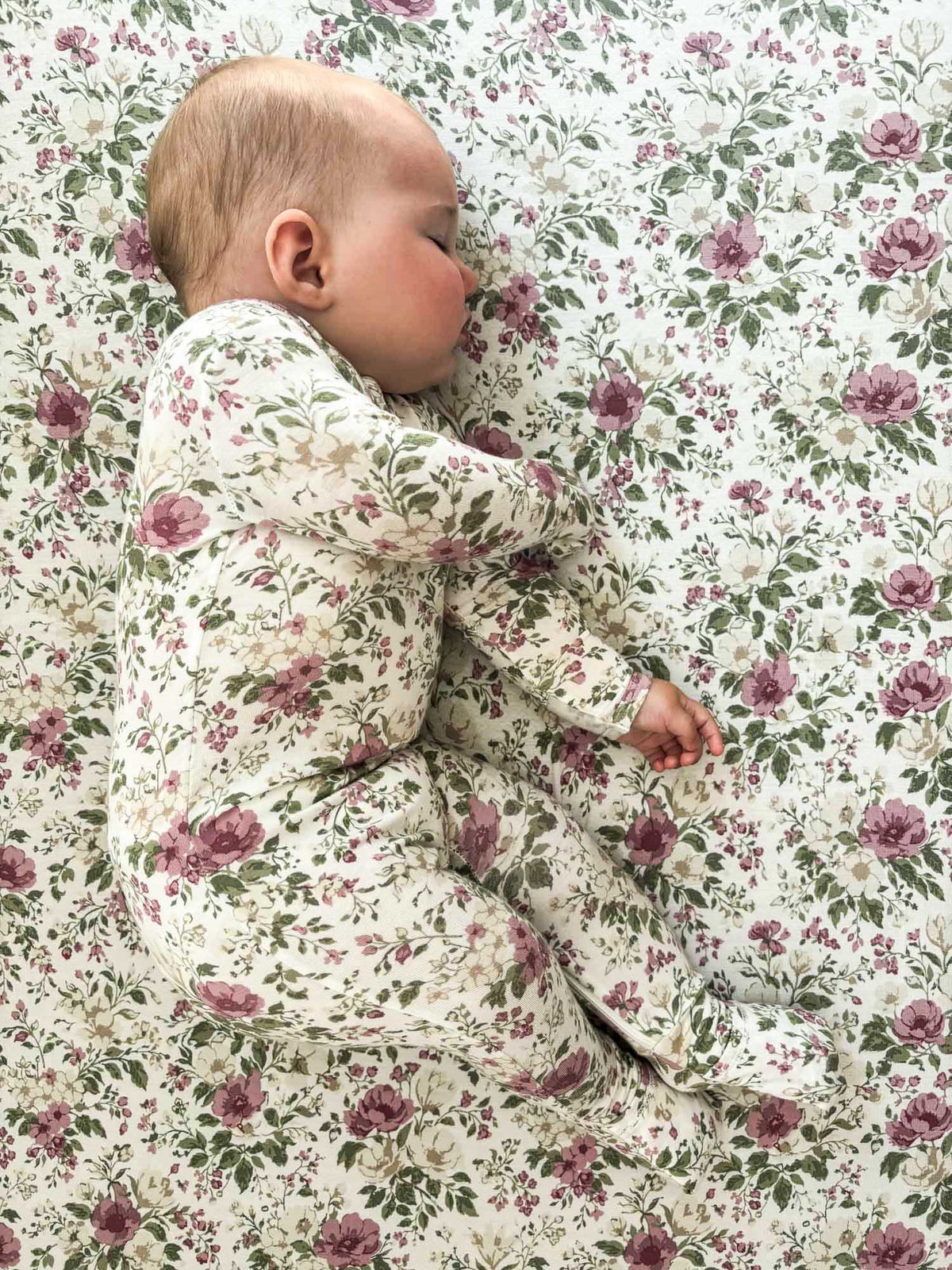 Floral crib sheet with mauve and pink rose pattern on light beige fabric