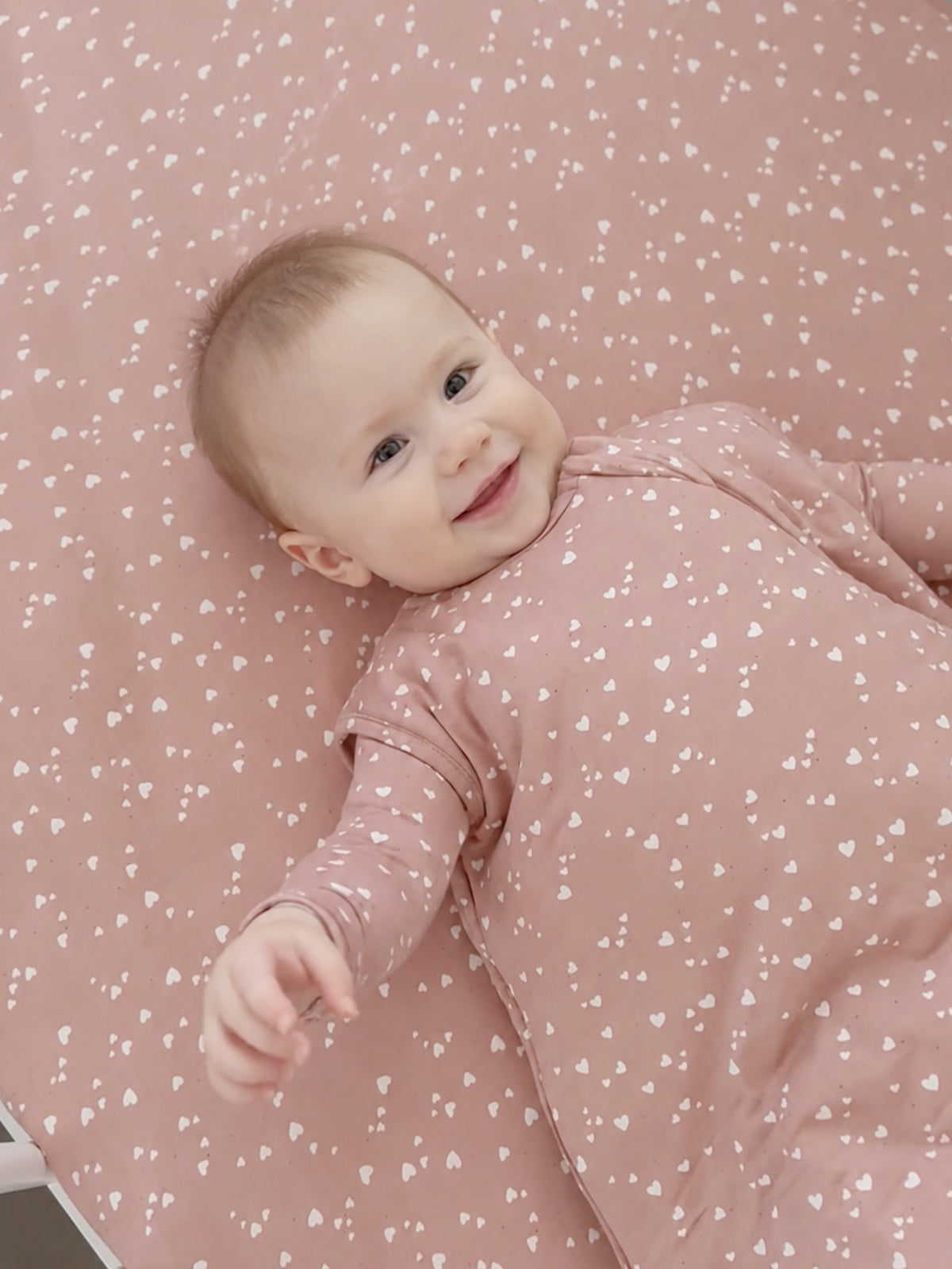 Pink baby sleep sack with small white heart print, long sleeves and front zip
