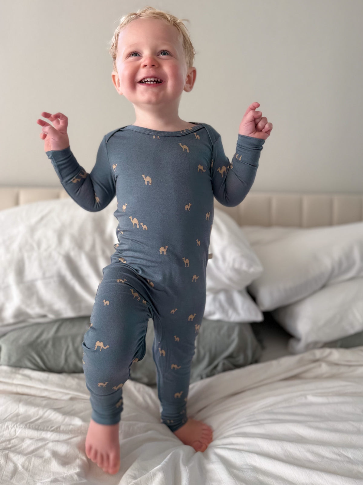 Navy camel-print footed pajama romper with long sleeves, toddler standing