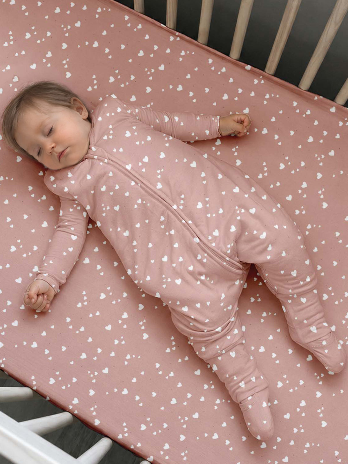 Pink heart-patterned footie sleep sack with long sleeves and enclosed feet