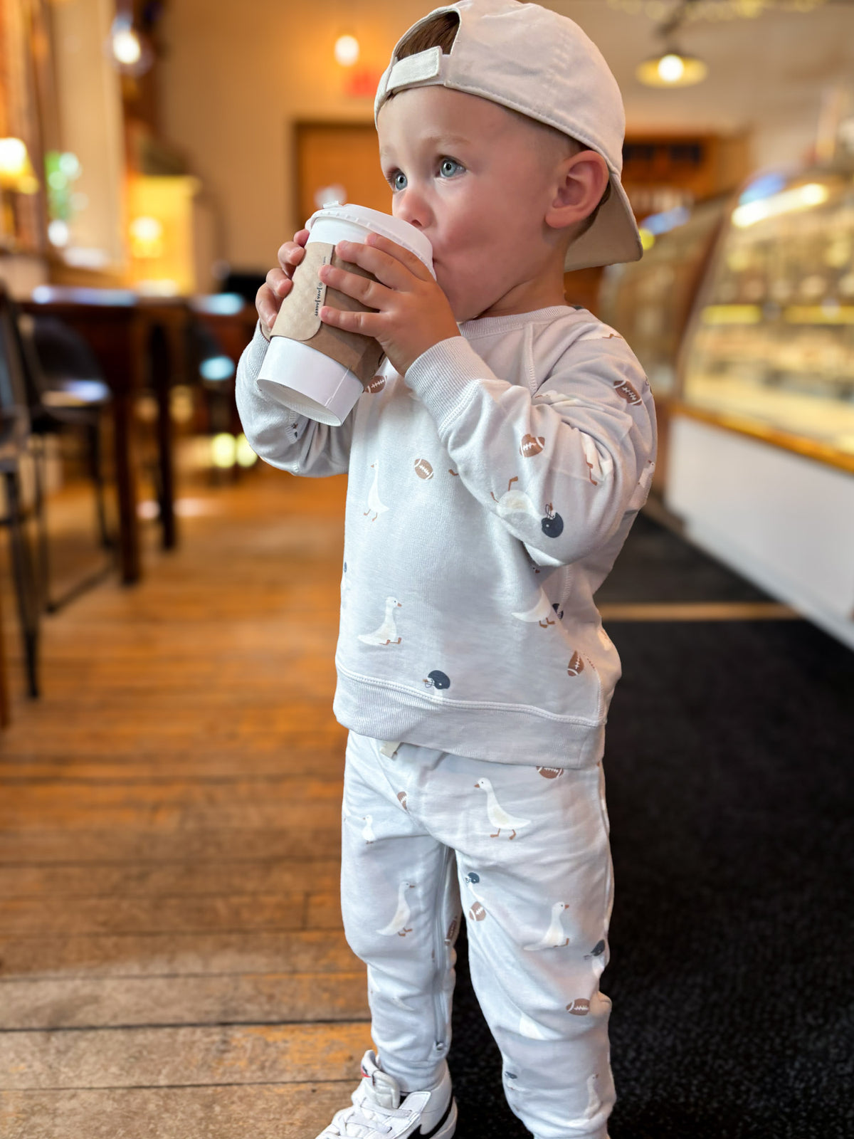 Kids fleece sweatsuit with duck and football print, toddler holding a cup