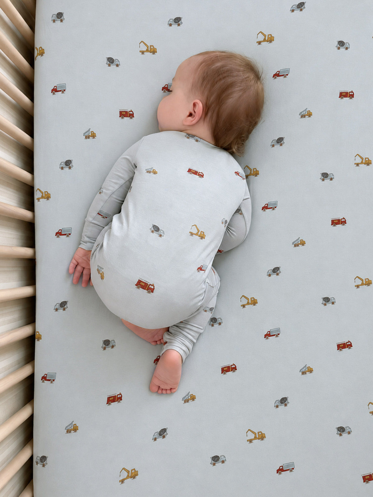 Light blue crib sheet with repeating construction vehicle print