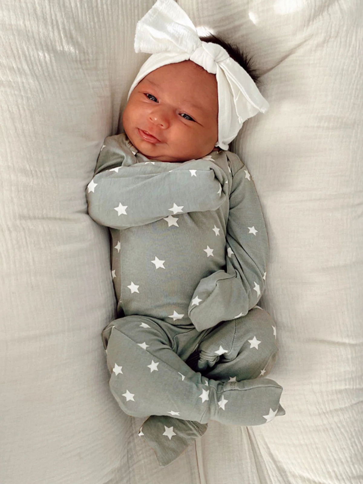 Sage green baby romper with long sleeves and white star print, tied hat