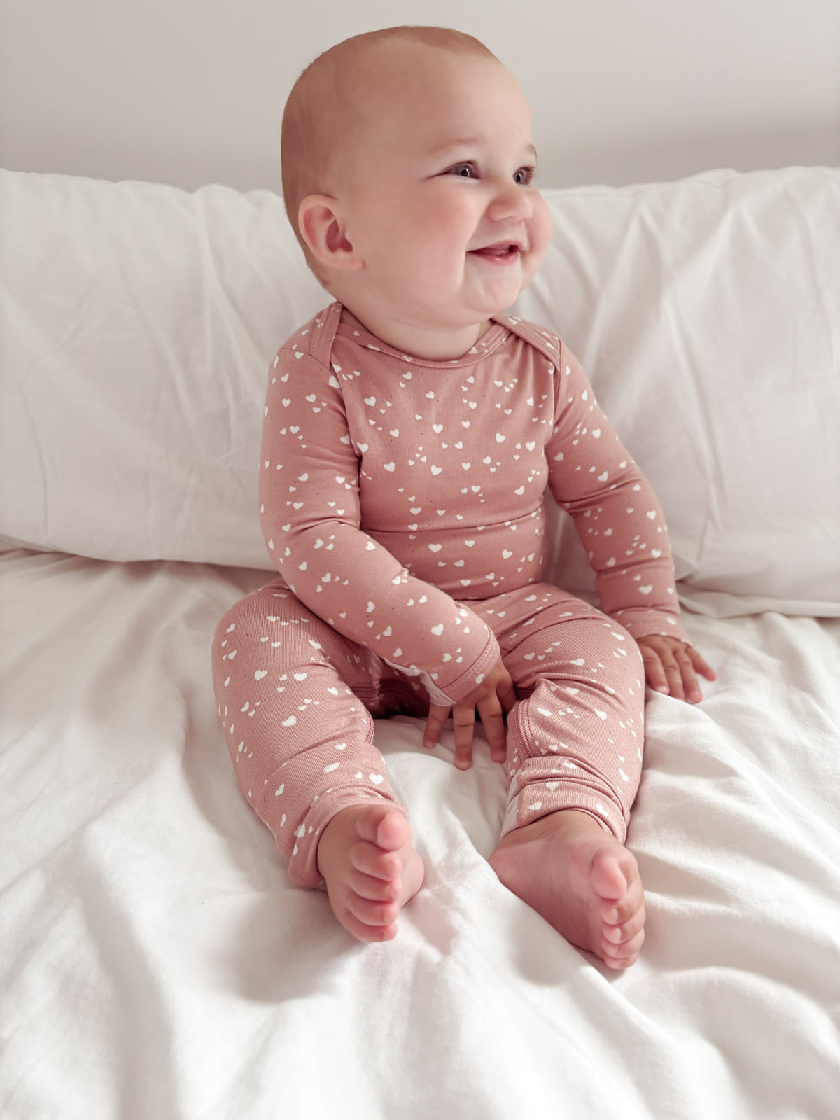 Dusty pink heart-print baby pajama romper with long sleeves and ankle cuffs