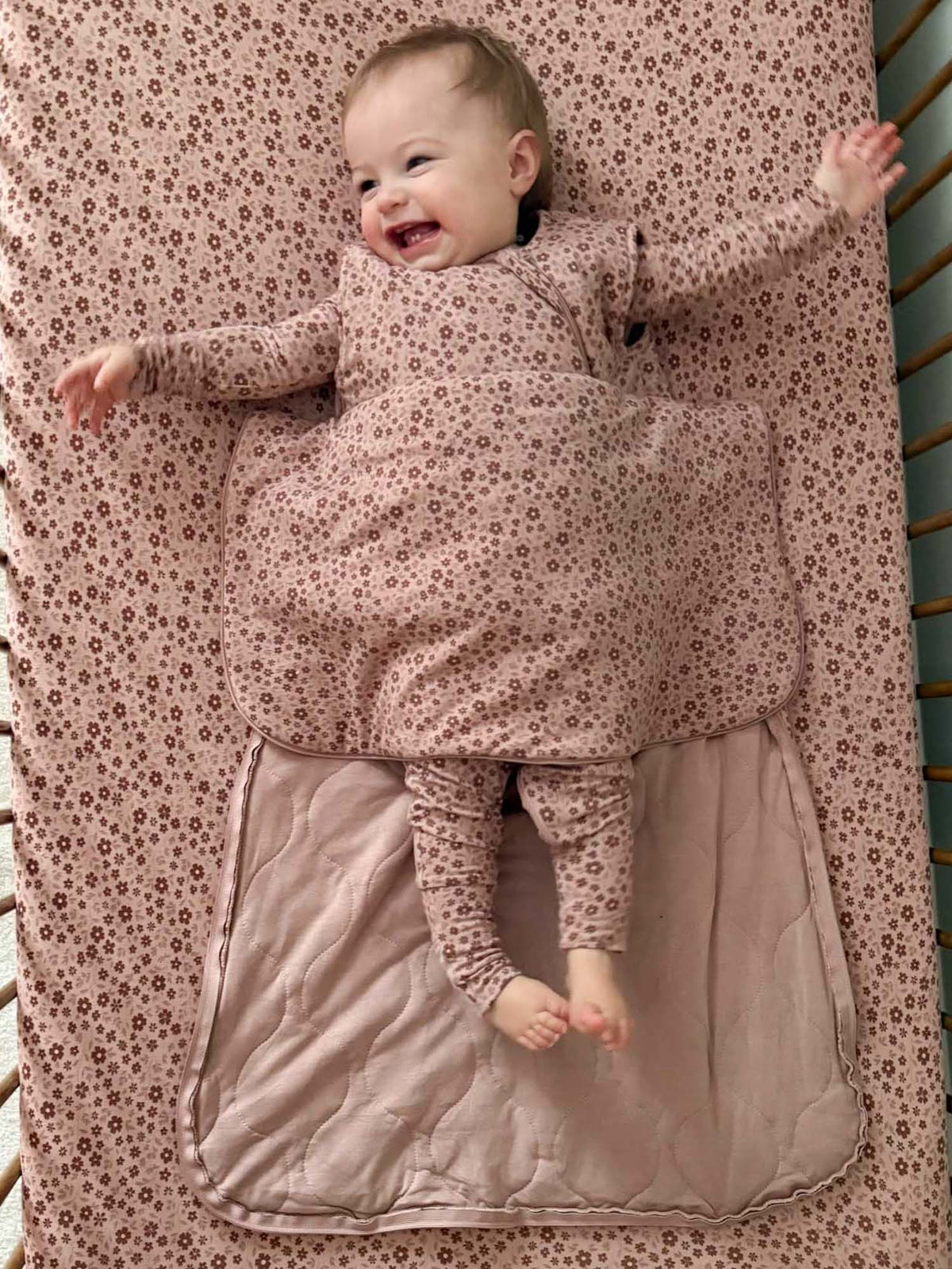 Baby sleep sack with petal print, front zipper, open hem showing inner lining