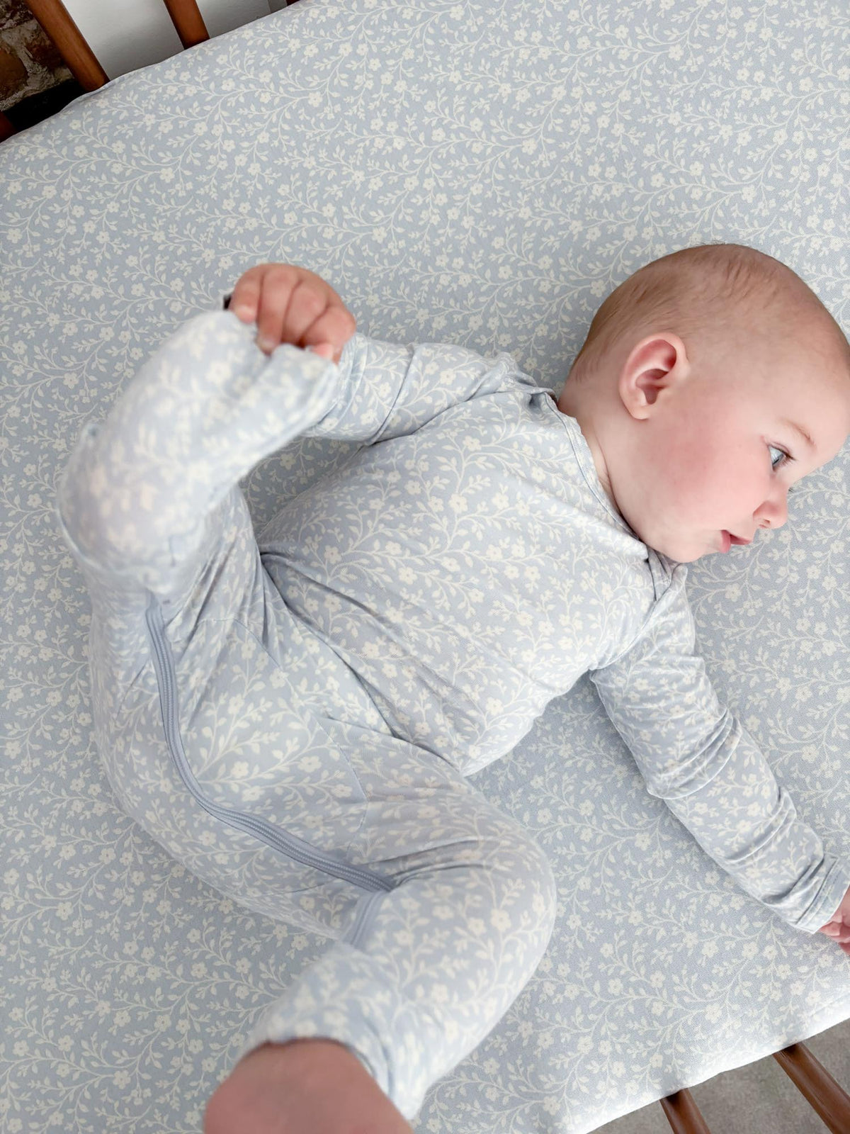 Light blue floral footed convertible pajamas with front zipper on baby.