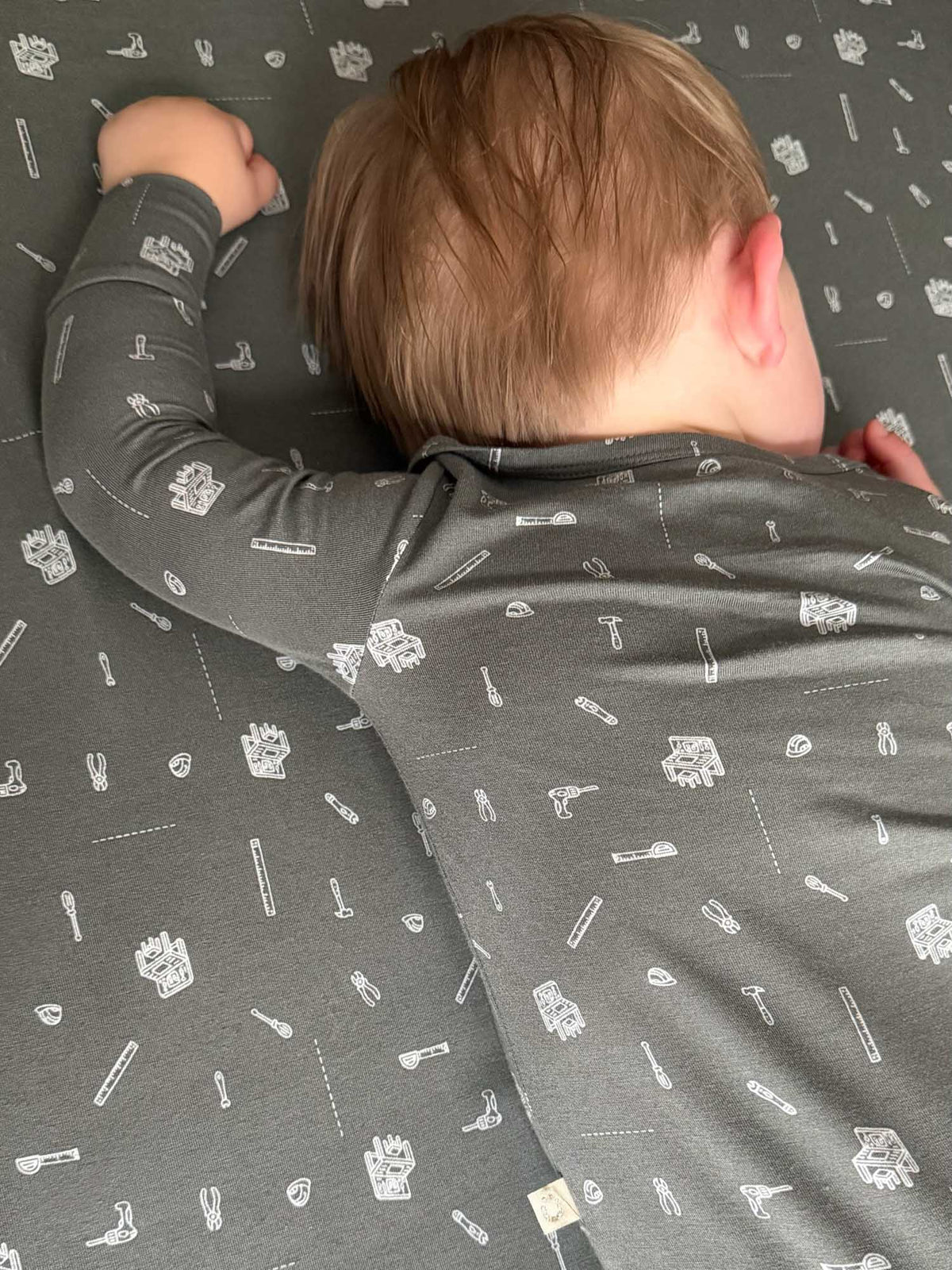 Close-up of grey crib sheet with white tool icons pattern