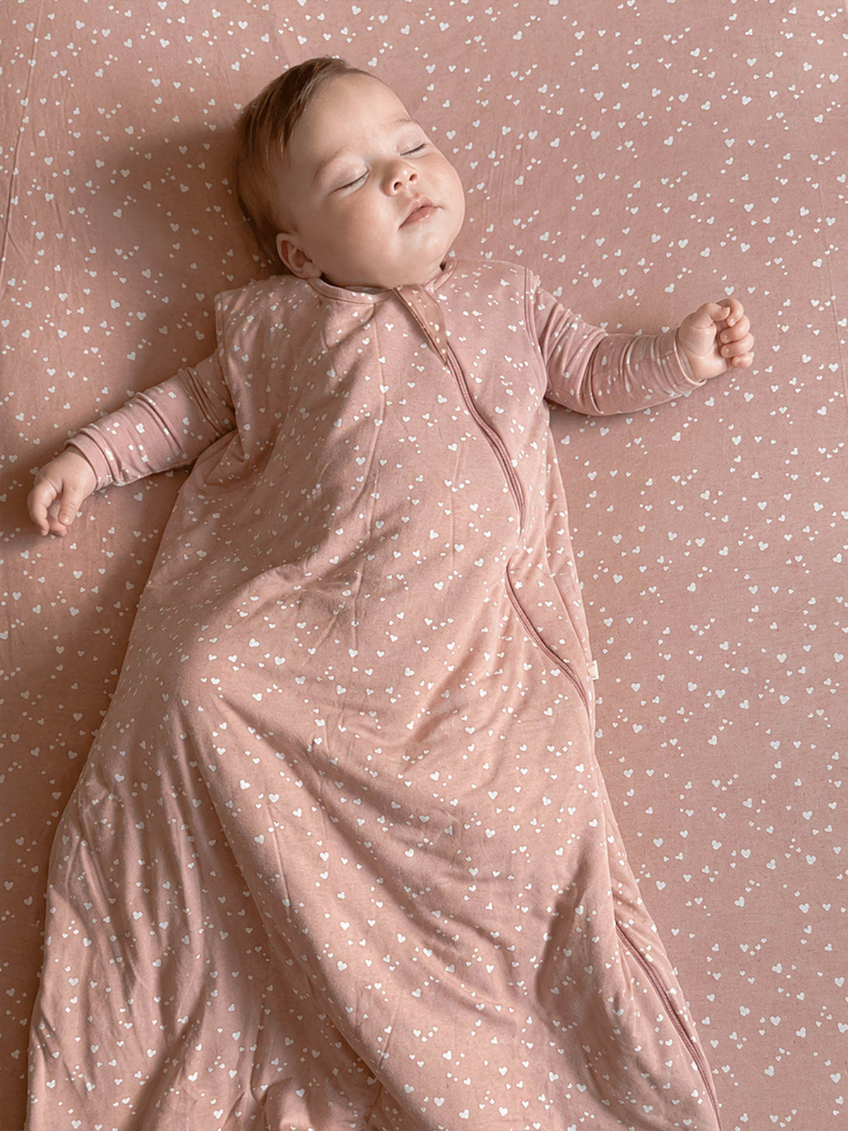 Pink baby sleep sack with all-over heart print, long sleeves and front zipper
