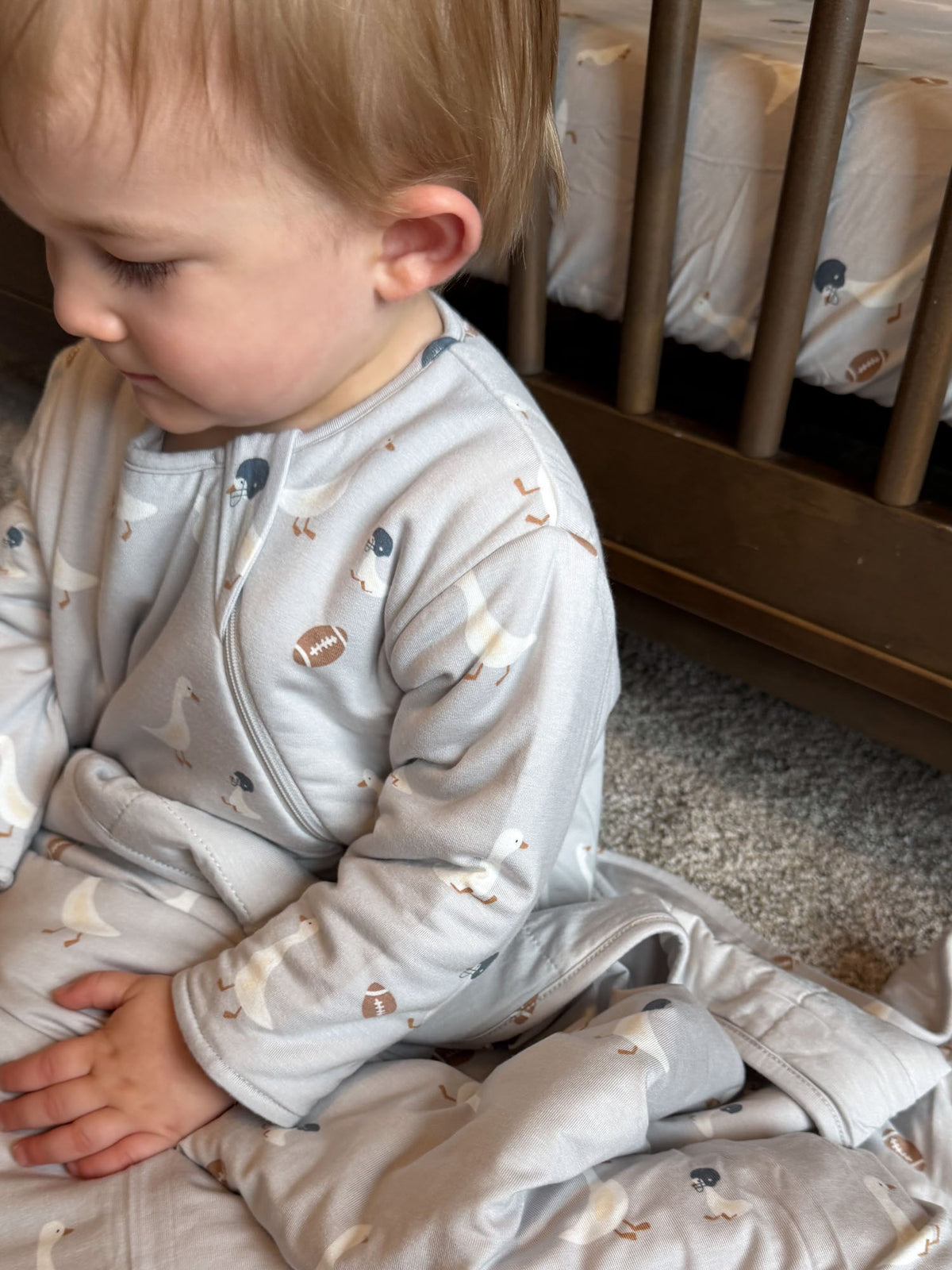Long-sleeve sleep sack with goose and football print, light gray, on baby