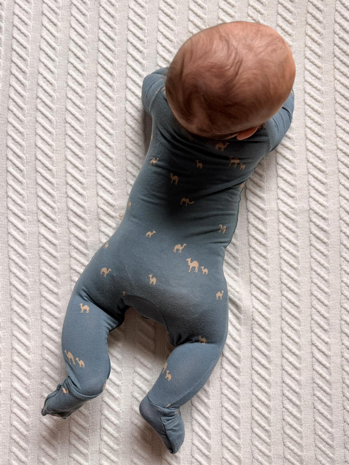 Navy camel-print footed pajama romper, toddler bent knees on bed