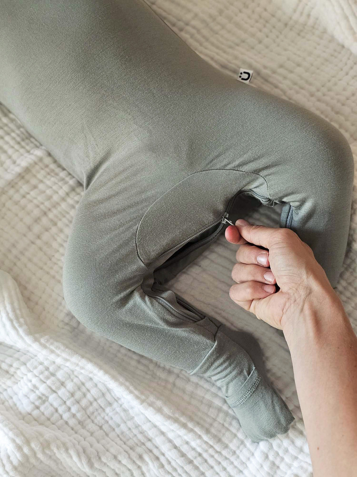 Sage green convertible pajama romper close-up of opening with hands adjusting fabric