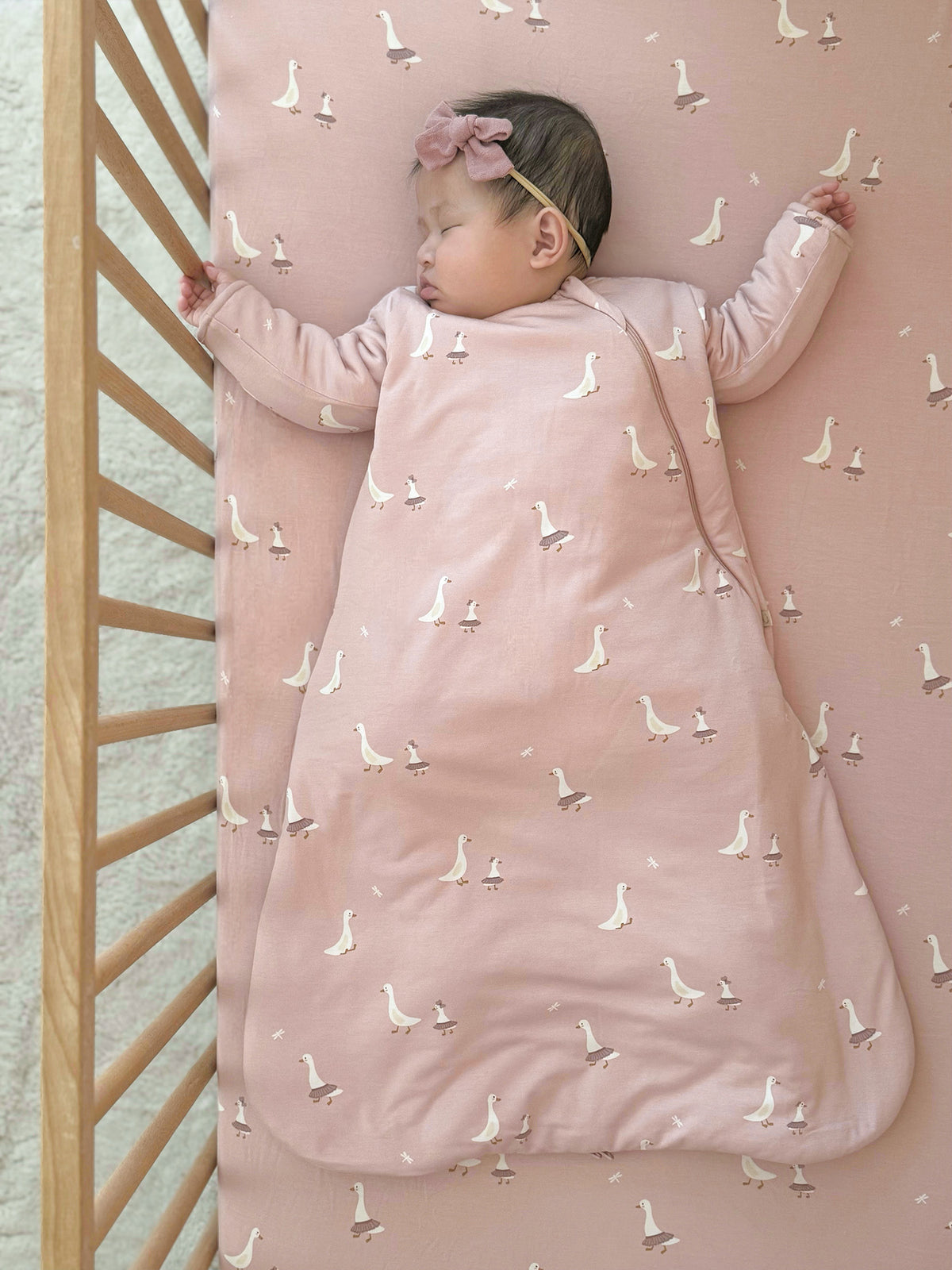 Blush pink long-sleeve sleep sack with white swan print and full front zip