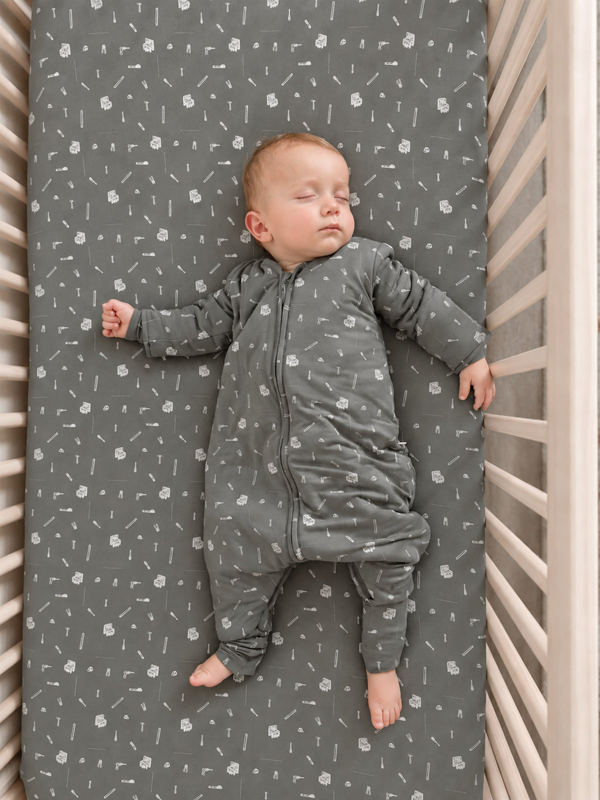 Gray long-sleeve footed sleep sack with white tool icons