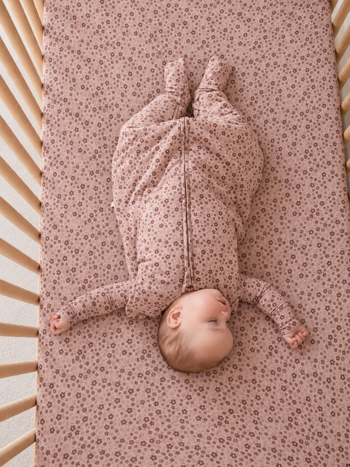 Light pink crib sheet with petal floral print, pleated corner