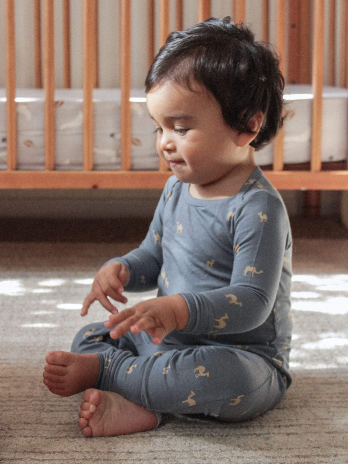 Navy camel-print footed pajama romper with long sleeves, toddler seated