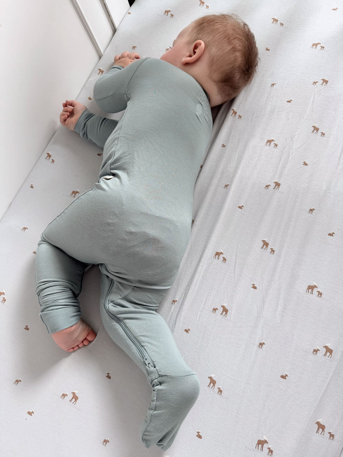 Light blue-green convertible footed pajama suit with long sleeves, baby lying on side