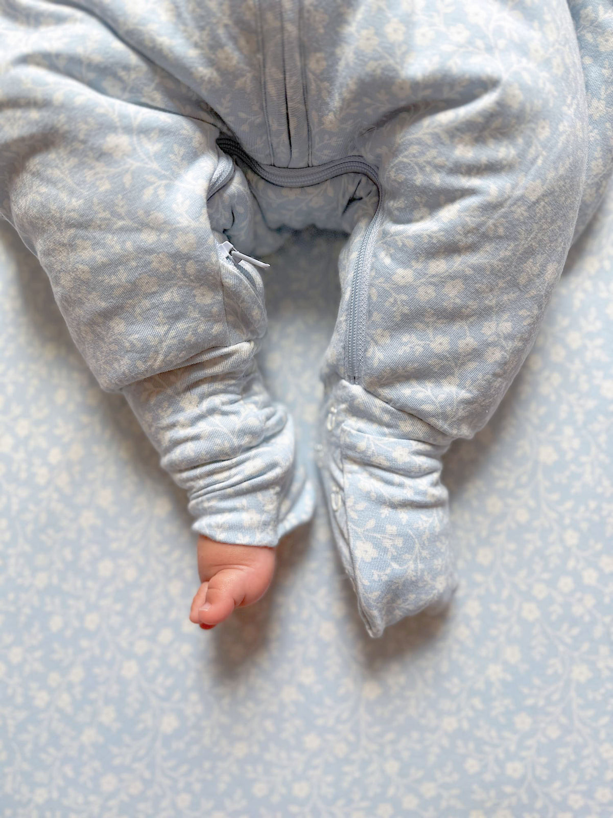 Close-up of light blue patterned footie sleep sack front zip and gathered sleeves